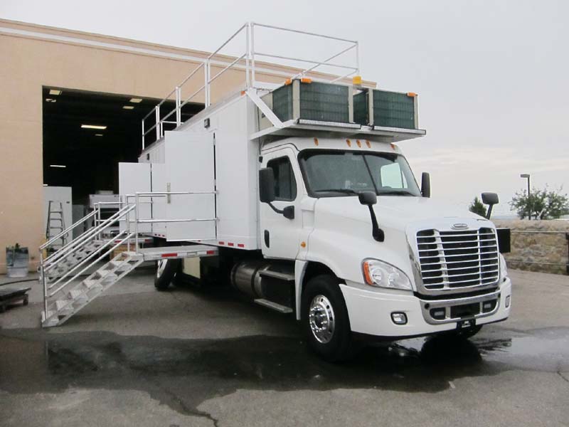 A white truck with two metal staircases on the right side