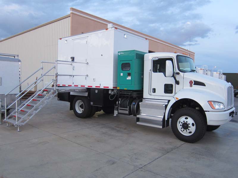 An all-white truck with a green machine attached in between the body and the tractor head