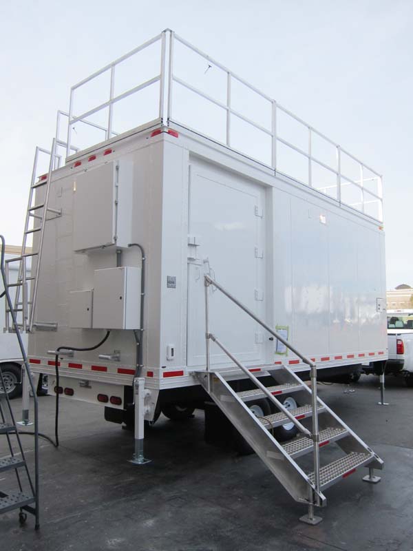 A white mobile shelter with a roof deck and a ladder